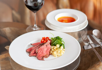 プレートに乗った肉料理と、付け合わせの野菜と赤ワイン