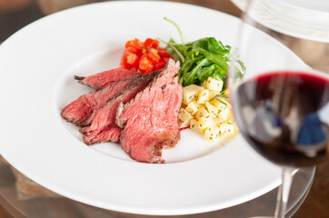 プレートに乗った肉料理と、付け合わせの野菜と赤ワイン
