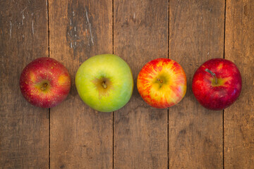 looking straight down on a variety of four apples on a farm table