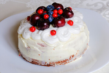 Delicious cake with whipped cream decorated with fresh blueberries and currants on a plate close up selective focus