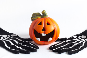 Orange decorative cheerful pumpkin lantern on a white background. Skeleton hand black gloves....