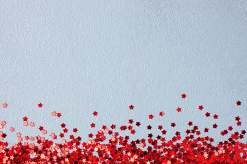 Red confetti on grey. Colorful Christmas or holiday background