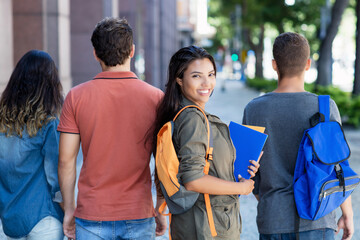 Junge Studentin aus Südamerika mit anderen Studenten vor der Uni