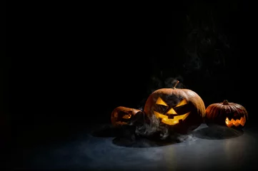 Keuken spatwand met foto Halloween card. jack o lantern with candles glow on a black background. A row of creepy pumpkins with carved grimaces smokes in the dark. © Михаил Решетников