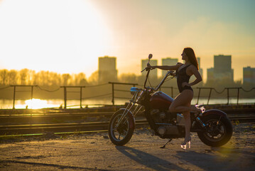 Red-haired woman in sexy lingerie in high heels sits on a motorcycle
