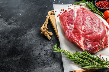 Raw brisket beef cut on a wooden cutting board. Black Angus beef. Black background. Top view. Copy...