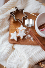 Christmas decor. Mug, Christmas candy, Christmas cookies, knitted sweater, wicker basket against the background of a Christmas tree. Cozy holidays.