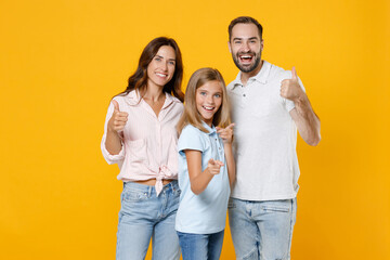 Smiling young parents mom dad with child kid daughter teen girl in basic t-shirts pointing index...
