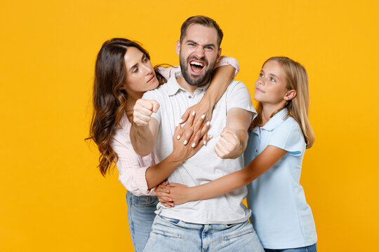 Crazy Young Parents Mom Dad Child Kid Daughter Teen Girl In Basic T-shirts Holding Hands Like Riding Car Hugging Isolated On Yellow Background Studio Portrait. Family Day Parenthood Childhood Concept.