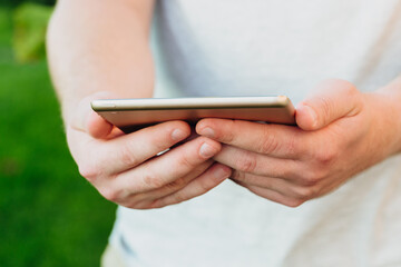 male hands holds digital pc t mock up for your text message or informational content, on the background of green nature