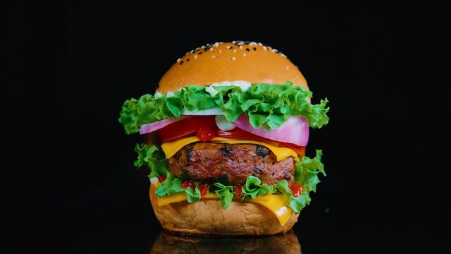 Hamburguesa jugosa y apetitosa con fondo de fuego. 240fps HD