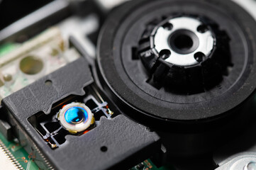 Macro close-up of a DVD drive head with a laser lens on the background of microcircuits....