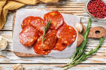 Spanish sliced chorizo sausage on a cutting board. cured meat. White background. Top view - obrazy, fototapety, plakaty