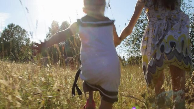 Two little girls running through summer field
