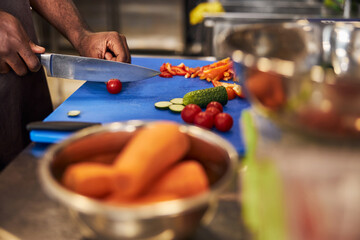 Chef cutting fresh vegetables for dish in restaurant