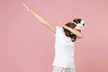 Young woman in white pajamas home wear sleep mask doing dab hip hop dance hands gesture, youth sign...