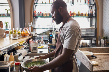 Professional male cooker working in open kitchen