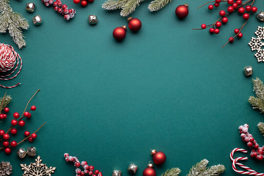 Christmas frame with classic red decorations. Fir branches, balls, jingle bells on green background.