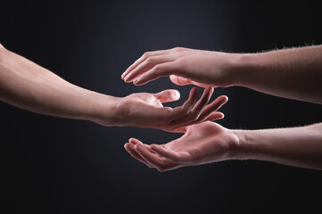 Two hands of one man in concern want to touch the hand of another man. The concept of caring in...