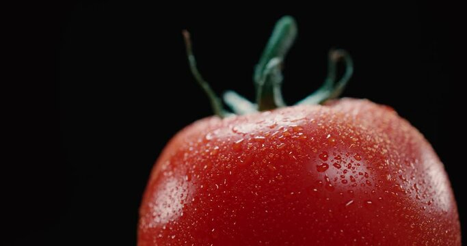 Tomate fresco y rojo girando en c&aacute;mara lenta en fondo negro. 4K