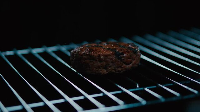 Parrilla con carne de hamburguesa con fuego de fondo. Cocinando carne de hamburguesa al grill. 240 fps HD