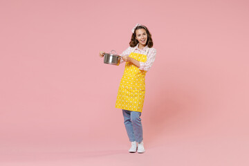 Full length portrait of cheerful young brunette woman housewife 20s wearing yellow apron hold...