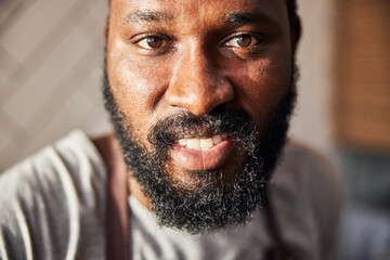 Smiling young bearded man cooking in cafe