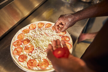 Male cooker making tasty pizza in restaurant