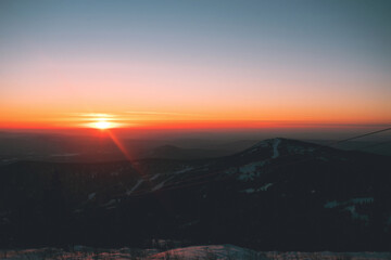Winter mountain landscape. Spruce taiga under the snow,mountain peaks and sunset sky. Panoramic view. Russia. Sheregesh.