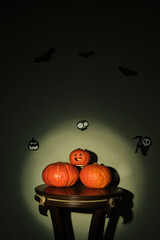 Colored pumpkins on wooden stool in front of a black backdrop