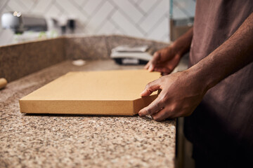 Male hands holding closed cardboard pizza box