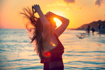 carefree woman in red swimsuit dancing at sunset on the beach. mature woman relaxation vitality healthy lifestyle