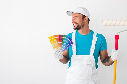 Cheerful painter with roller and samples