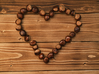 Close up shot of chestnut side by side forming a heart on a wooden table 