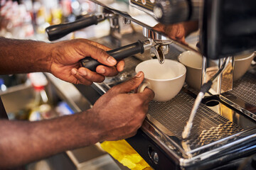 Bartender making fresh coffee with professional coffee machine