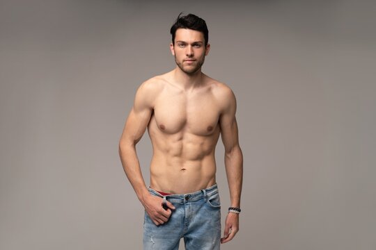 Portrait of a well built shirtless muscular male model against white background