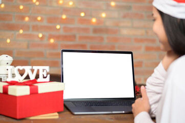 Young smiling woman wearing red Santa Claus hat making video call on social network with family and friends on Christmas day.
