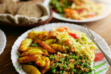 Ordering simple food at home. A serving of green string beans, fried potatoes and lettuce in one plate.