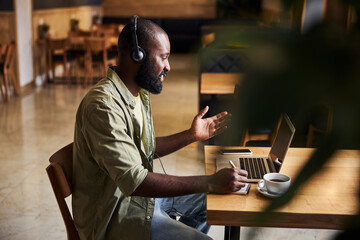 Handsome Afro American man talking with colleague through video call