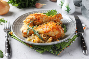 Baked chicken drumsticks with cabbage and garlic on gray plate. Horizontal format.