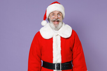 Fototapeta na wymiar Surprised elderly gray-haired Santa Claus man in Christmas hat red suit coat glasses keeping mouth open isolated on violet purple background studio. Happy New Year celebration merry holiday concept.