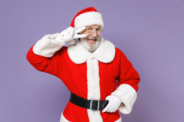 Excited gray-haired Santa Claus man in Christmas hat red suit coat white gloves glasses showing victory sign isolated on violet background studio. Happy New Year celebration merry holiday concept.