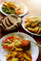 A simple meal on a plate at a diner. Salad, fried potatoes and meat cutlet. Quick and delicious lunch