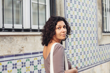 Fototapeta na wymiar Young woman walking in Lisbon, azulejo tiles on the traditional Portuguese house