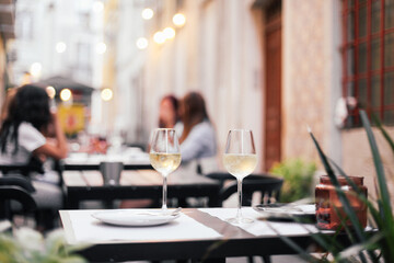 Two glasses of wine on a outdoor table, cozy evening, small street in Europe