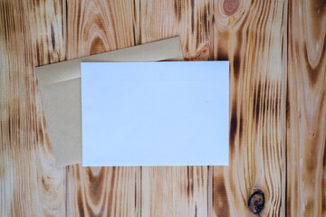 White greeting card mock up on the wooden table with craft envelope, place for a text.