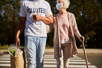 Reliable volunteer helping aged person with crossing the road
