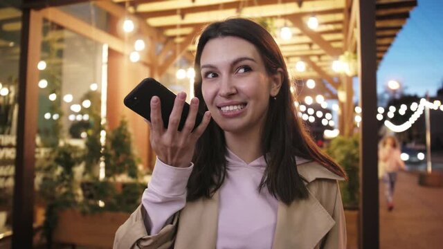 Woman tourist voice recognition ai sending audio message on cellphone phone at night city street speech helper commander.