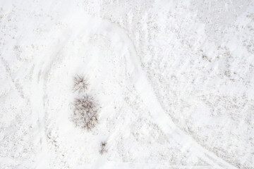 Natural background of a snow-covered area with a lone shrub in the center. Shooting from a drone.