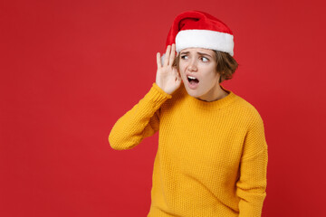Curious young Santa woman in yellow sweater Christmas hat try to hear you overhear listening...